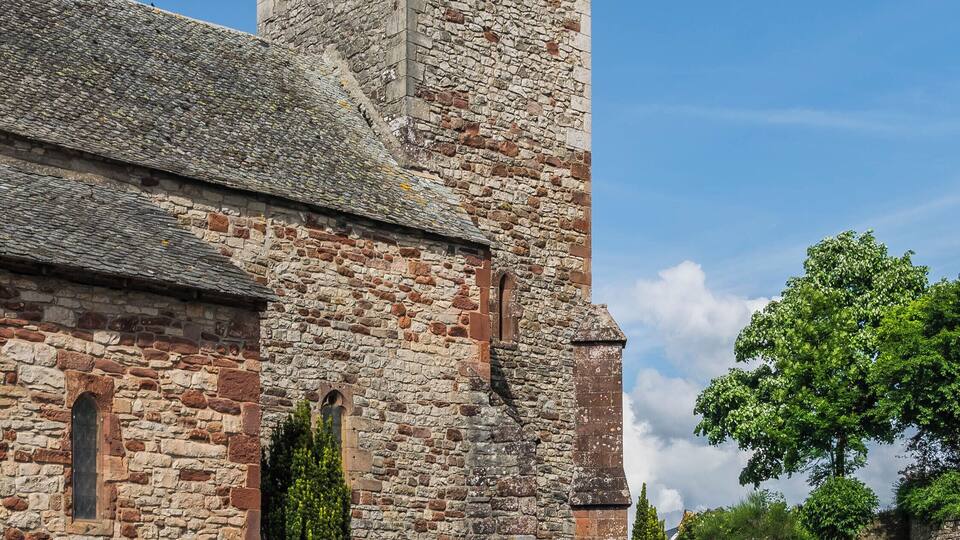 A stone church with a bell tower and a cross on top.