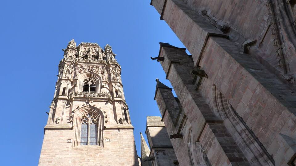 A tall, ornate church tower with intricate carvings and a large arched window.