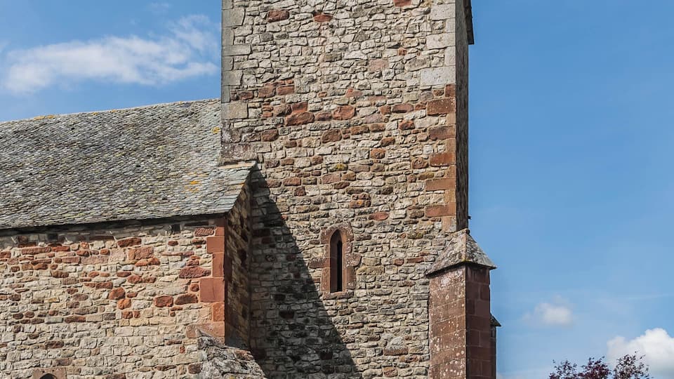 A stone church with a bell tower and a weather vane.