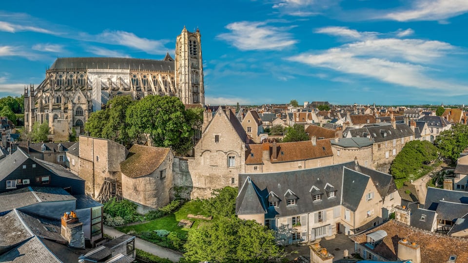 A historic cathedral with a tall bell tower, surrounded by a densely packed urban area with traditional European architecture.