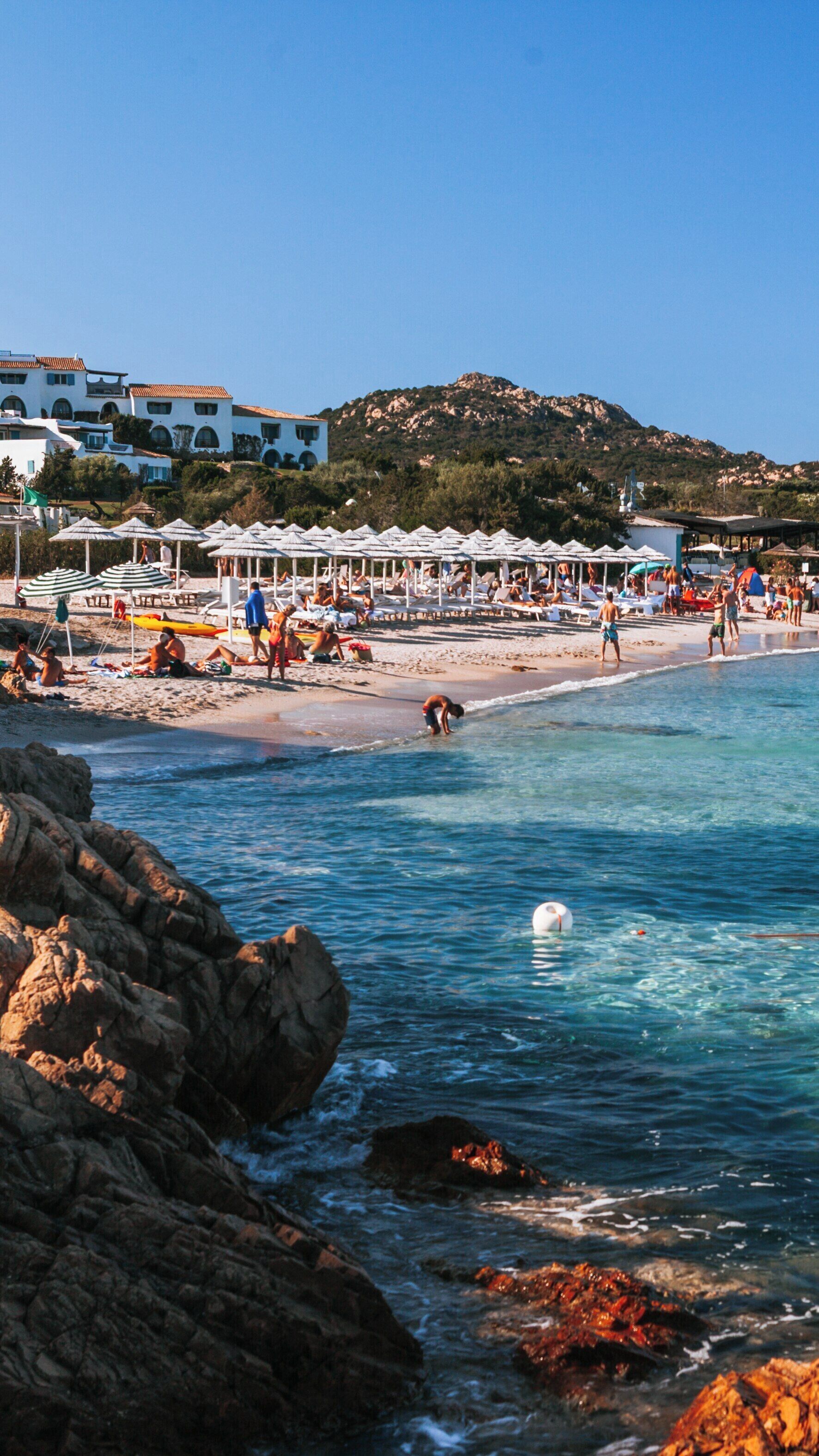 Relaxing day at Romazzino Beach in Arzachena, Sardinia with clear waters and sunbathers enjoying the coastal charm