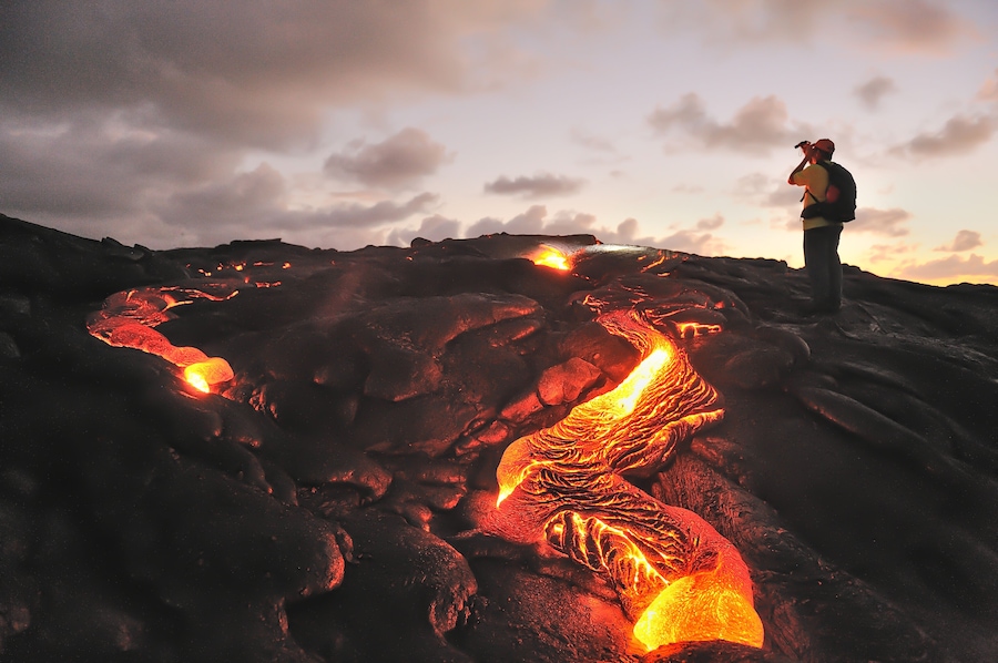 A person observing flowing lava at a volcanic site.