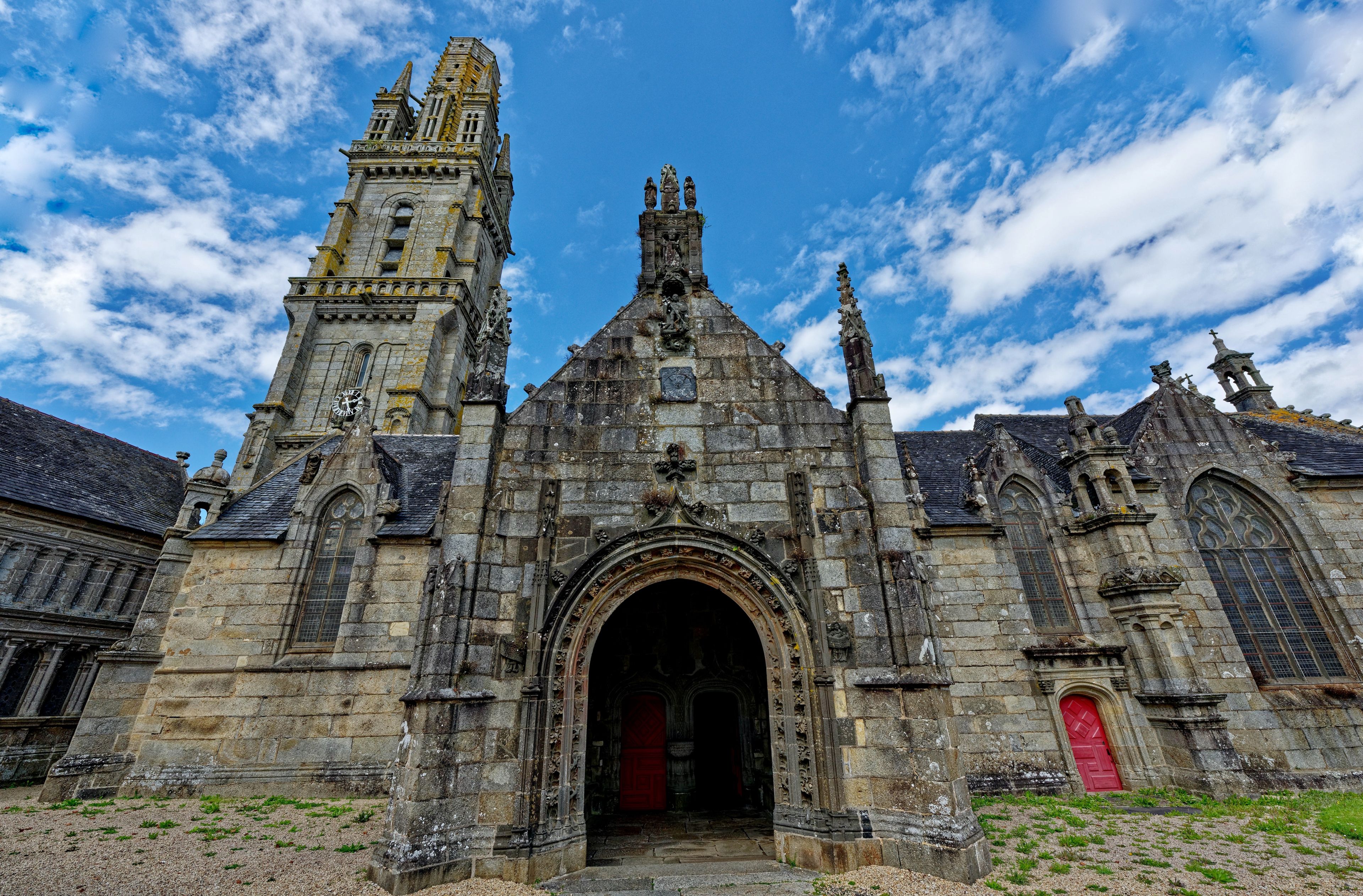 Une église historique en pierre, dotée d’un imposant clocher et de détails architecturaux complexes.