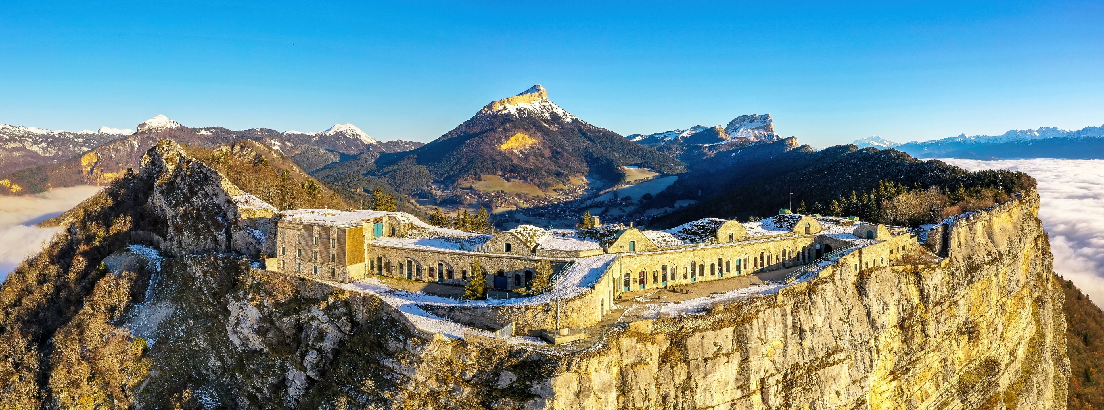 A mountain fortress with snow-covered peaks and a valley below.