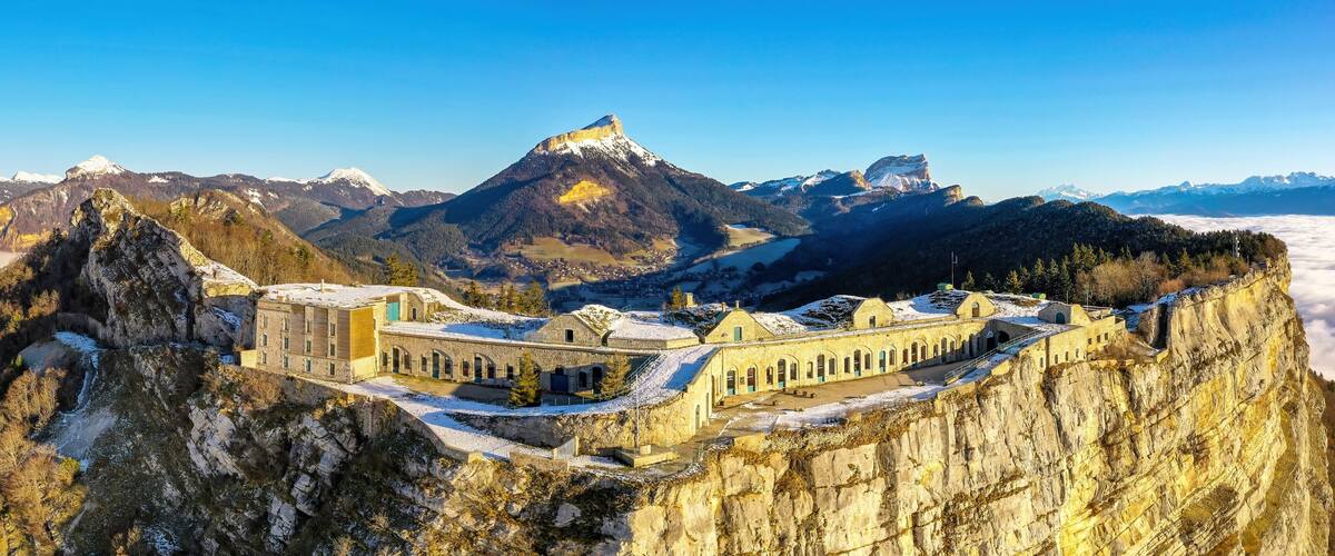 A mountain fortress with snow-covered peaks and a valley below.