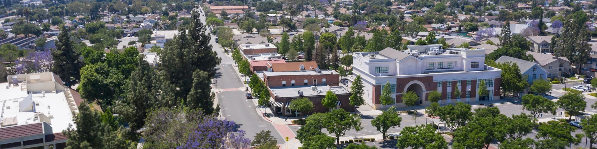 A suburban area with a prominent building with a red roof, surrounded by trees and a parking lot.