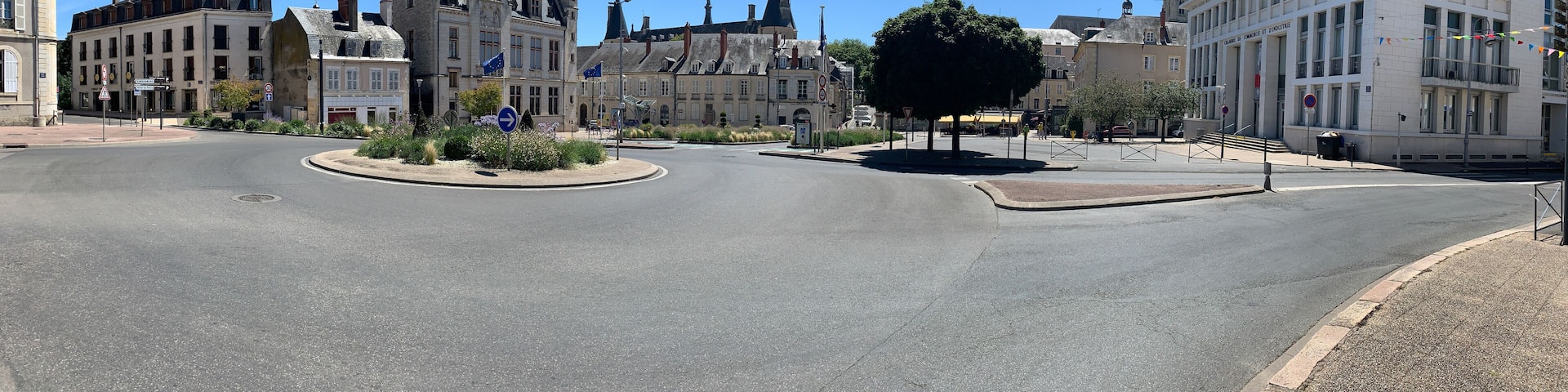 A roundabout with historic buildings, including a prominent Gothic-style structure with multiple spires.