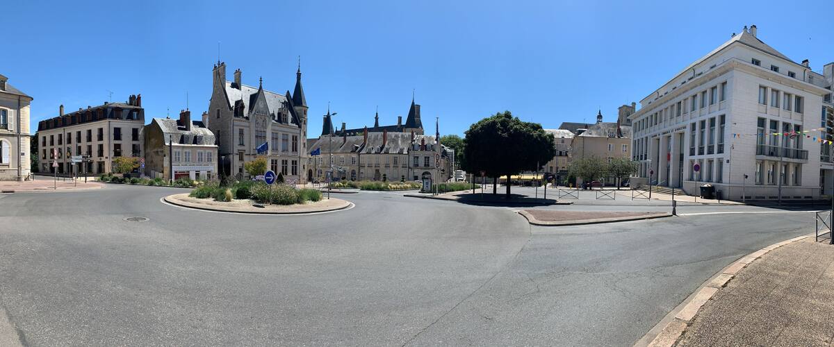 A roundabout with historic buildings, including a prominent Gothic-style structure with multiple spires.