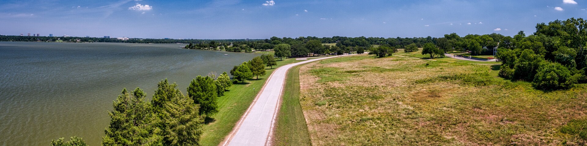 Una carretera costera con un lago, árboles y cielo despejado.