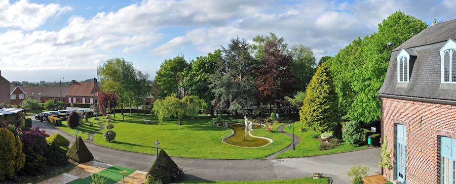 A residential area with a well-maintained lawn, a winding water feature, and a variety of trees.