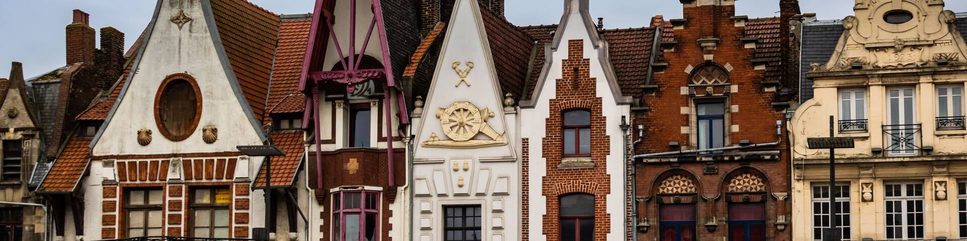 A row of historic European buildings with varied architectural styles, including pointed roofs and decorative facades.