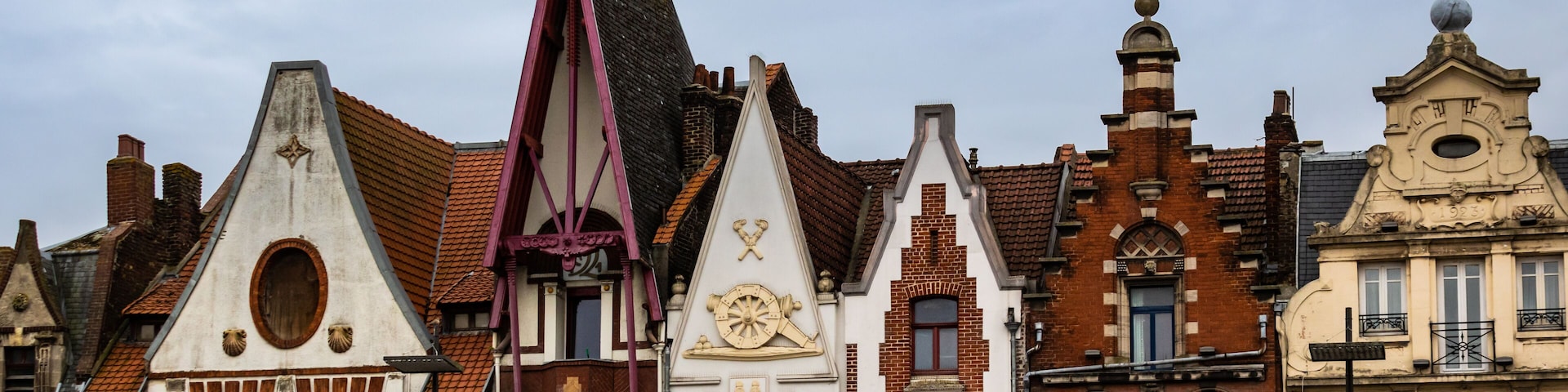 Una hilera de edificios europeos históricos con diversos estilos arquitectónicos, incluyendo techos puntiagudos y fachadas decorativas.