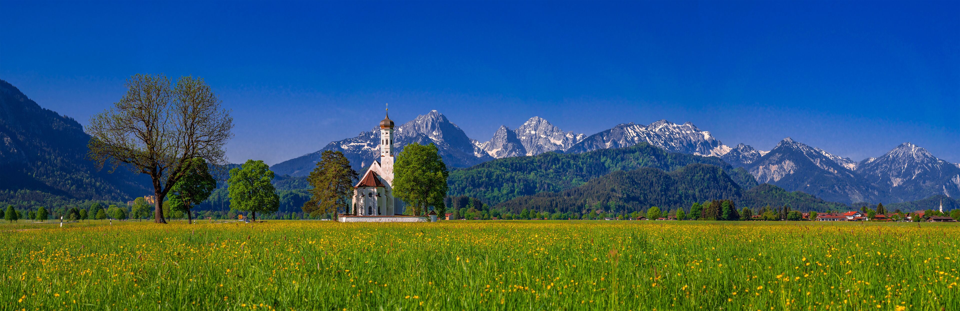A church in a field with a mountain range in the background.