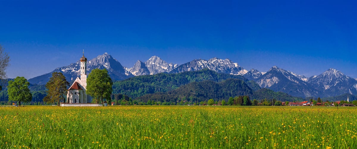 A church in a field with a mountain range in the background.
