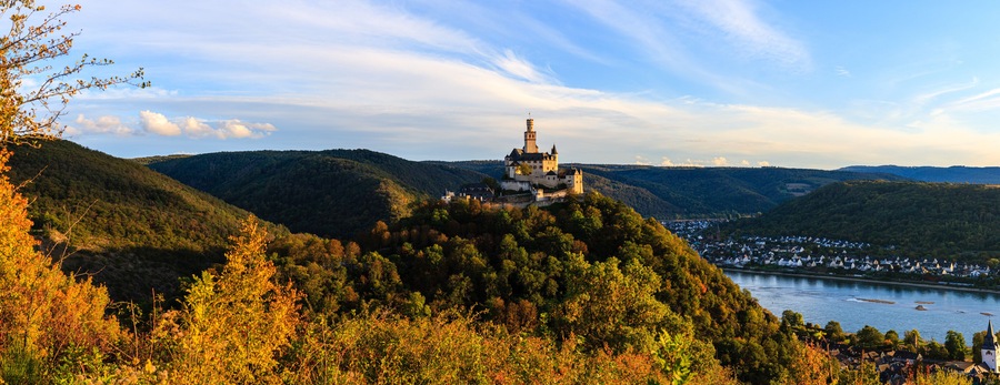 A castle on a hill overlooking a river and a town.