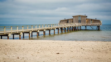 Un muelle de madera que lleva a una casa de playa sobre pilotes en el agua.