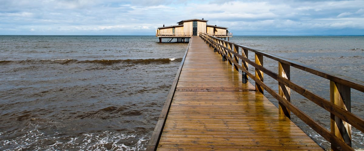 A wooden pier leading to a wooden structure over water.