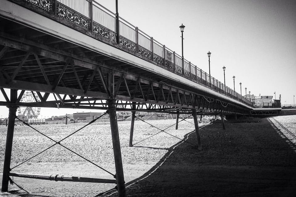 Un muelle con estructura metálica, barandillas y farolas.