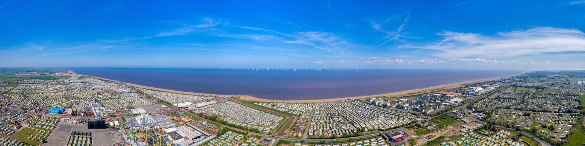 An aerial view of a coastal area with a large marina, numerous mobile homes, and a beach.