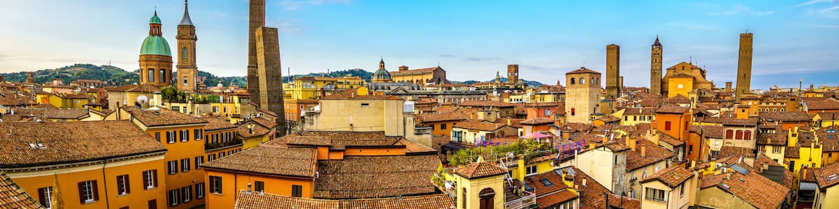 A historic cityscape with prominent towers, domed buildings, and terracotta-roofed structures.