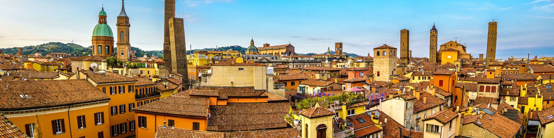 A historic cityscape with prominent towers, domed buildings, and terracotta-roofed structures.