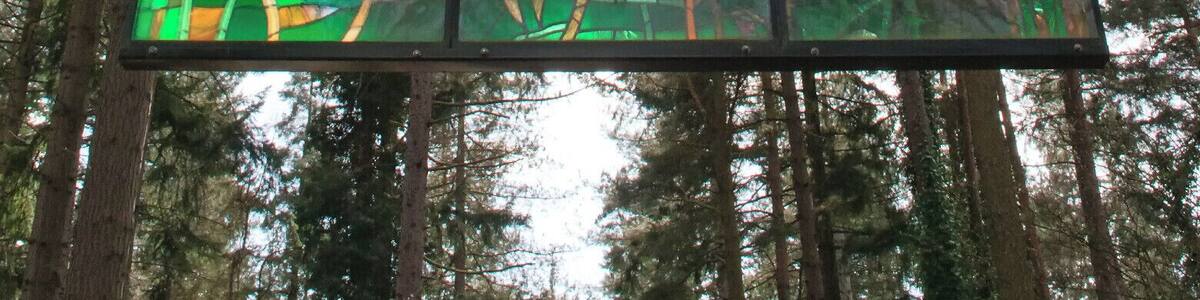 A stained glass window with vibrant colors and forest scenery.