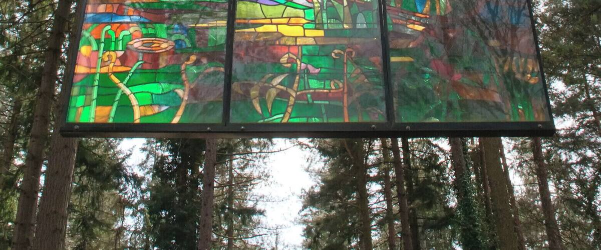 A stained glass window with vibrant colors and forest scenery.