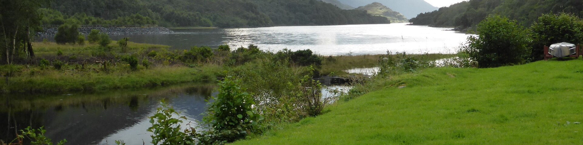 Un lago rodeado de colinas y montañas verdes.