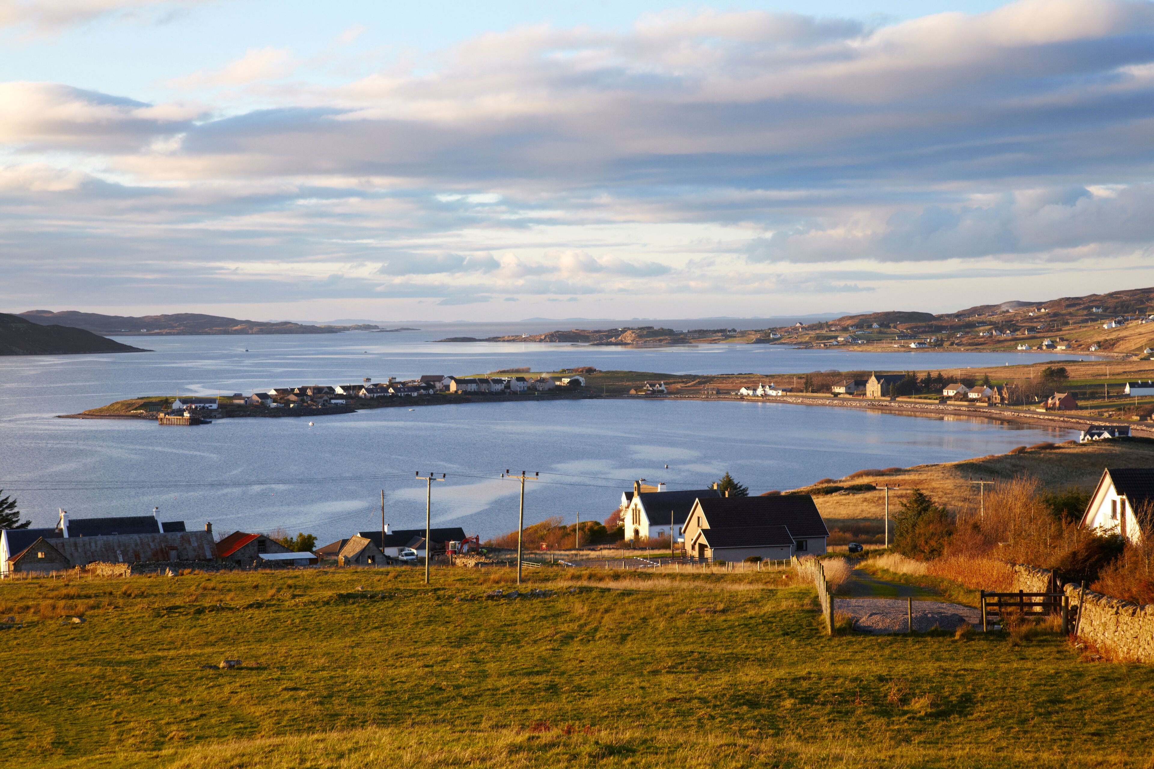 A coastal village with houses, a harbor, and a large body of water.