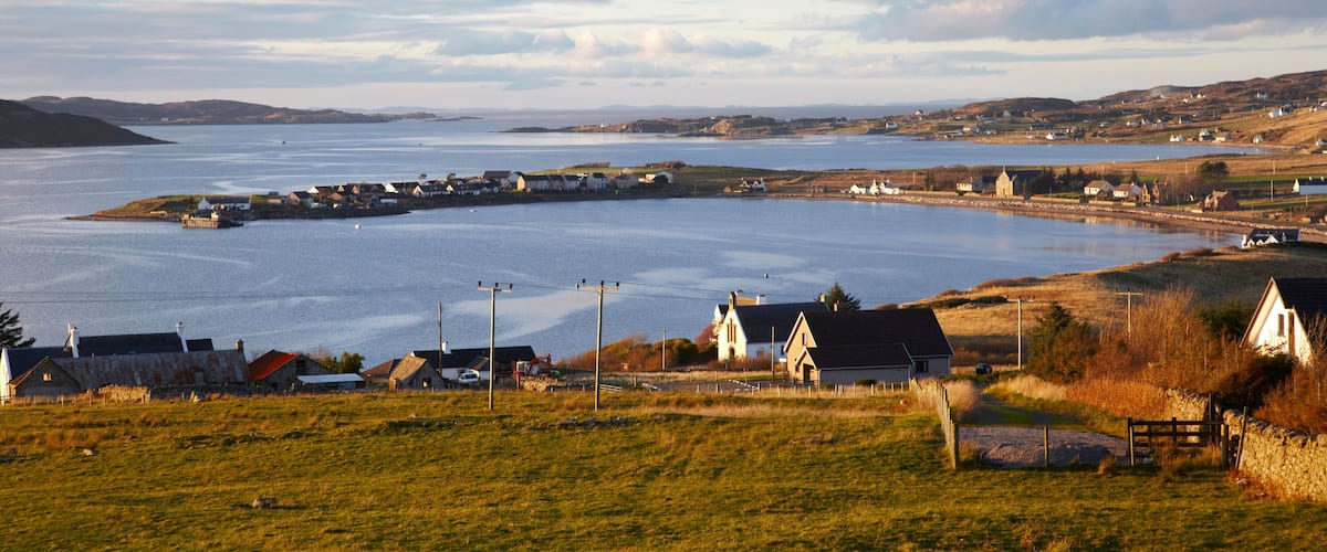 A coastal village with houses, a harbor, and a large body of water.
