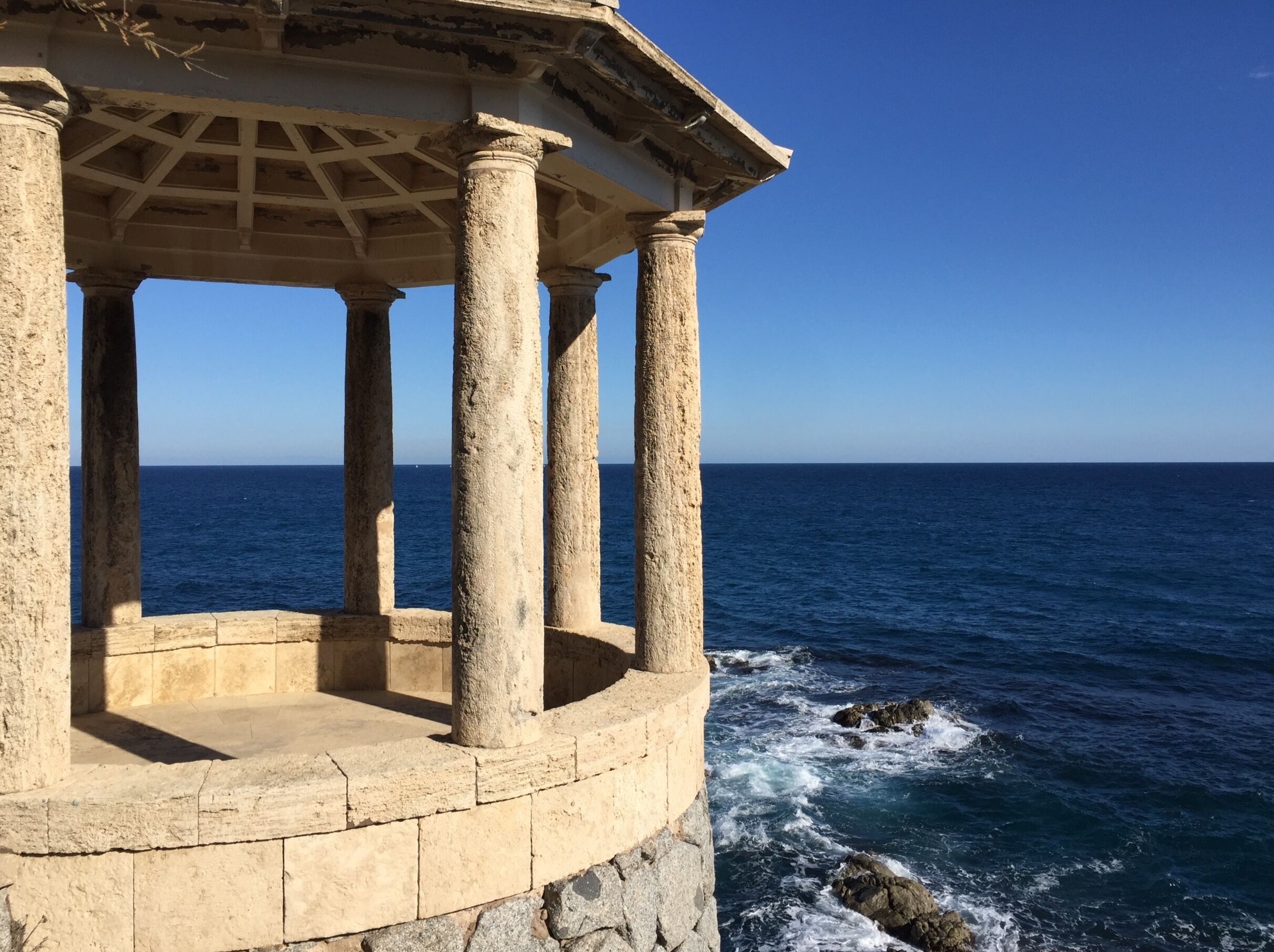 Une construction en pierre, dotée de colonnes, qui surplombe la mer.