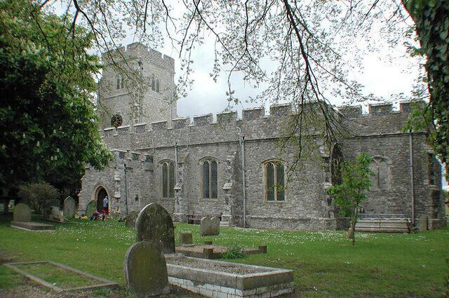 A historic stone church with a tower and arched windows, surrounded by a cemetery with headstones.