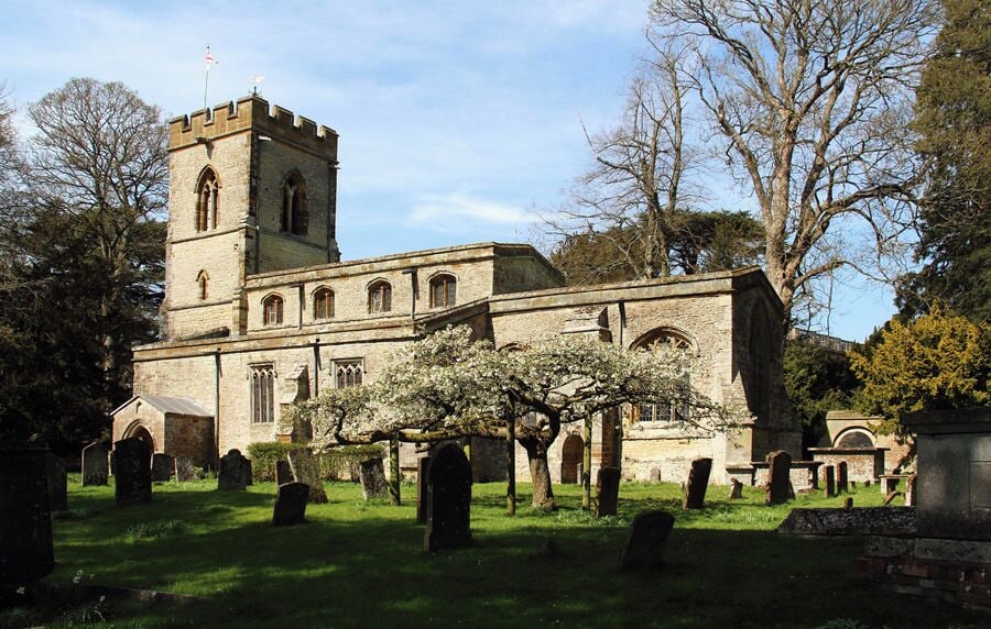 A historic church with a prominent tower and a cemetery in the foreground.