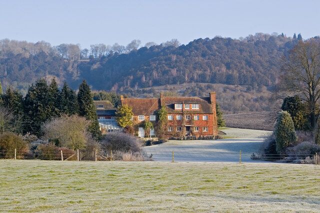 A large red brick house with a white fence in a rural setting.