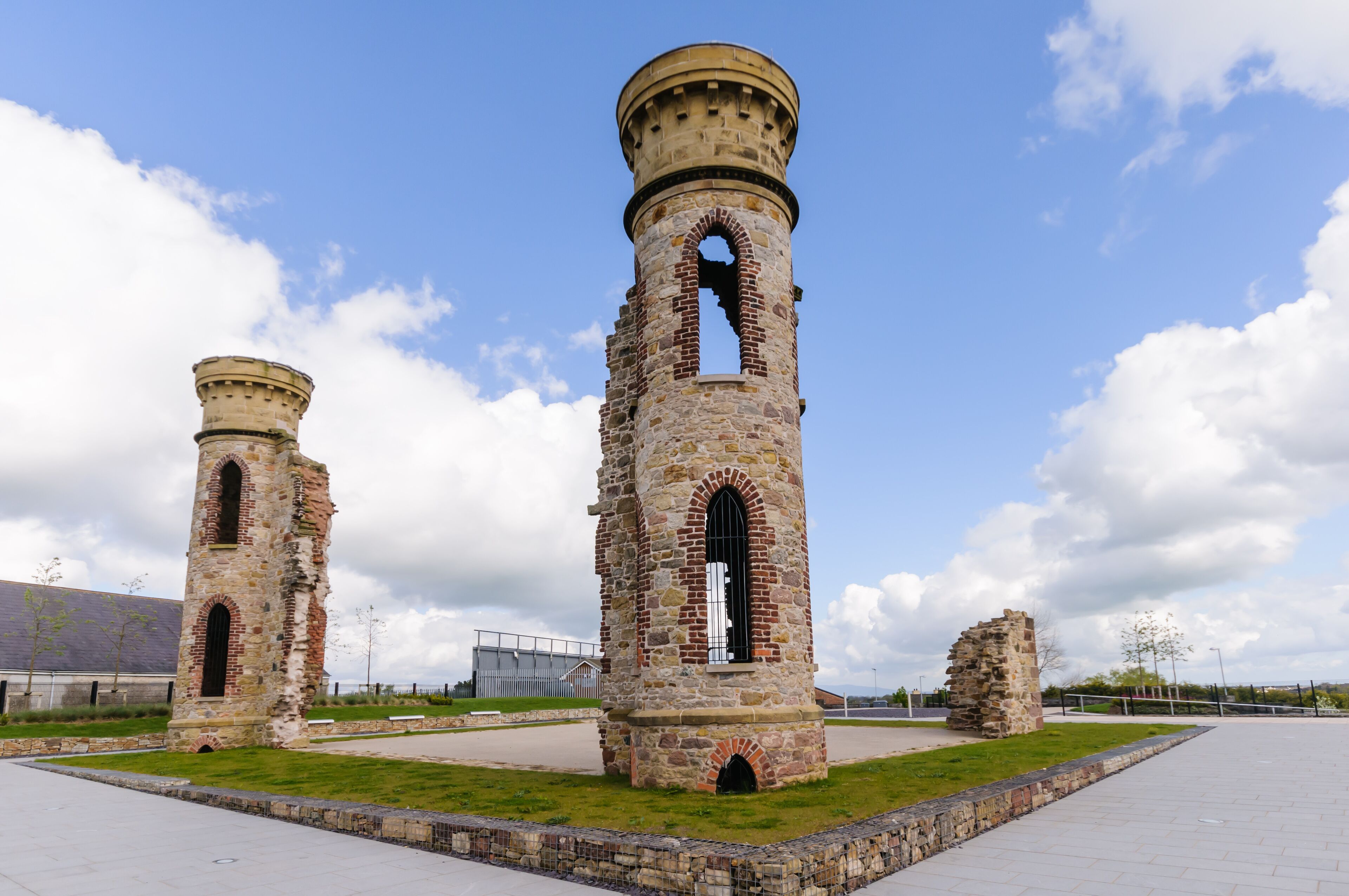 Two stone towers with arched windows and a grassy area in the foreground.