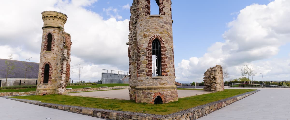 Two stone towers with arched windows and a grassy area in the foreground.