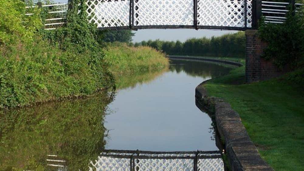 A canal with a bridge and a grassy bank.