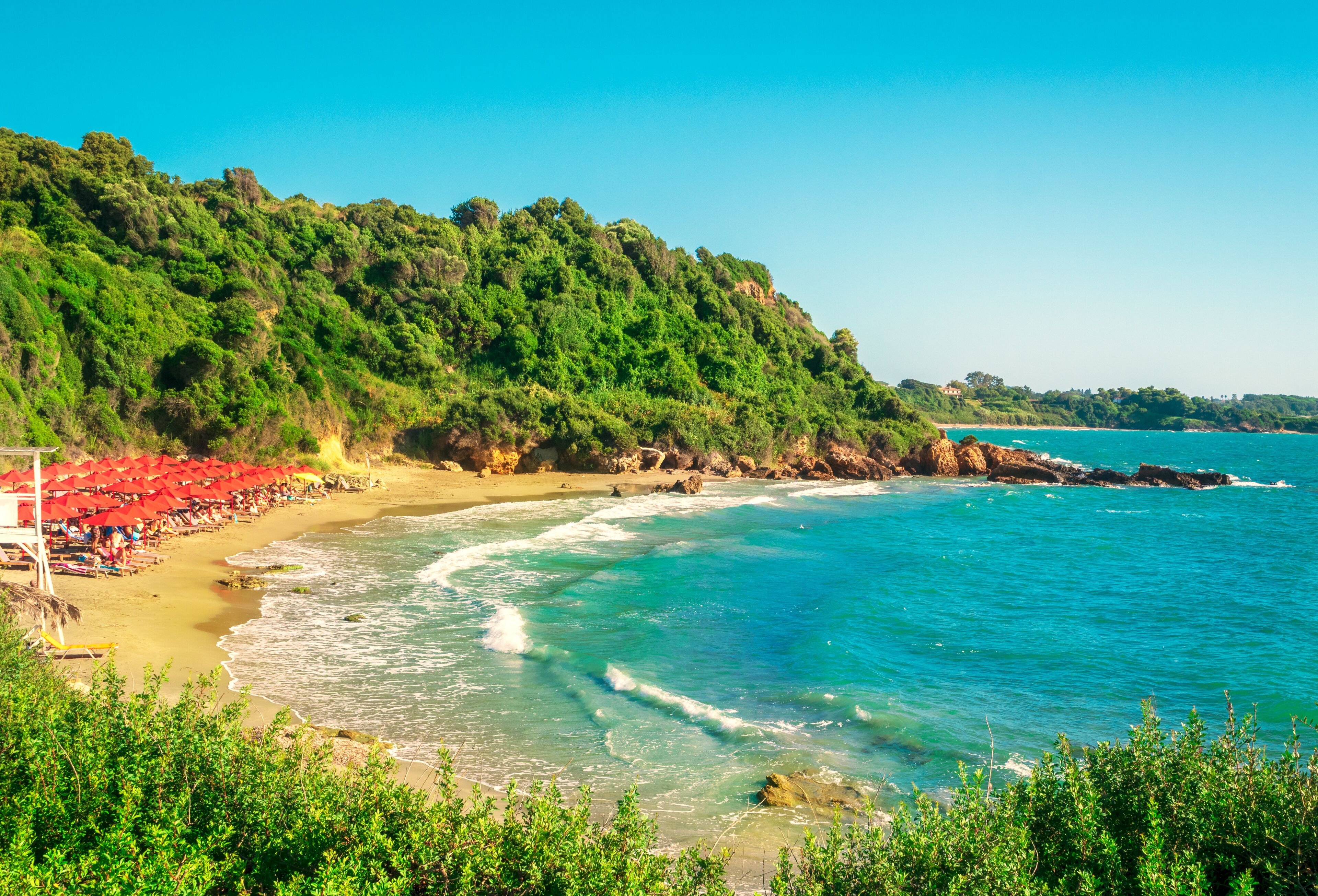 A vibrant aerial view of Skafidia Beach, Peloponnese, Greece, illuminated by the golden rays of the Greek summer sun.