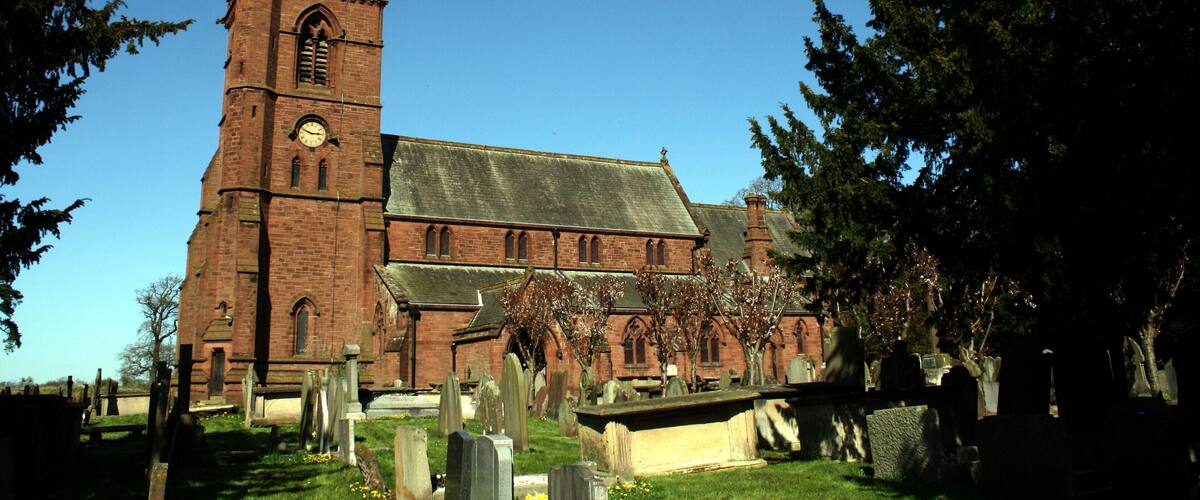 A large brick church with a tall steeple and a clock tower.