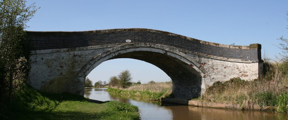 An old brick bridge over a calm river.