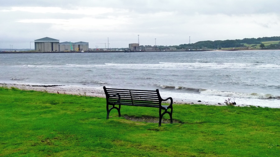 A bench by a beach with waves crashing onto the shore.
