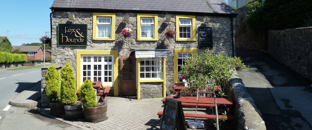 A stone building with a sign reading "Fox & Hounds."