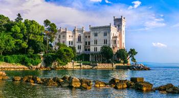 Un château historique situé au bord d’une mer paisible, avec des rivages rocheux et une végétation luxuriante.