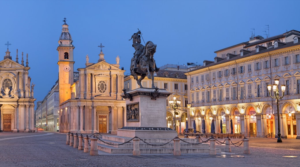 Uma praça histórica com uma igreja imponente, uma estátua e arquitetura clássica.