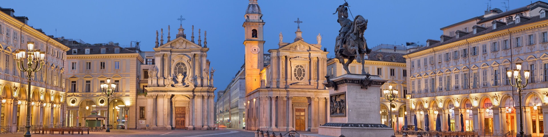 Una piazza storica con una chiesa importante, una statua e architettura classica.