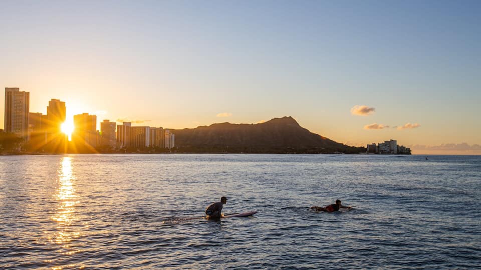 Waikiki showing surfing, a sunset and general coastal views
