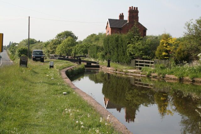 A narrow canal with a bridge, a house, and a car parked nearby.