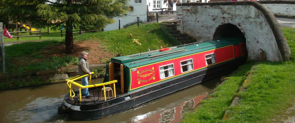 A narrowboat on a canal, a bridge, and a pub named "The Kings Lock" in the background.