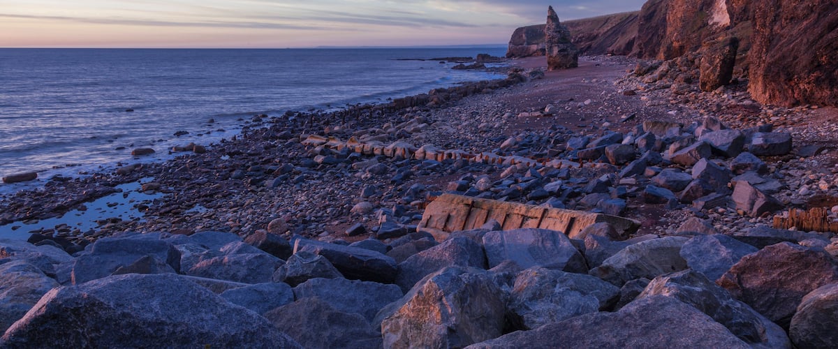 A rocky coastline with large boulders and a cliff.