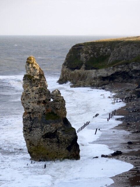 A coastal rock formation with a narrow path beside the sea.